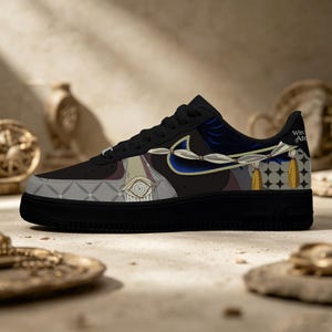 Puede incluir: Zapatillas Air Force 1 negras con ilustraciones personalizadas. El diseño presenta un ojo, detalles en azul y borlas doradas. El texto "Witch Ate" es visible en el talón. La zapatilla tiene suela y cordones negros.