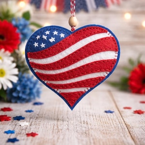 Puede incluir: Adorno de fieltro en forma de corazón con diseño patriótico. Presenta la bandera estadounidense con rayas rojas y blancas y un campo azul con estrellas blancas. Cuelga de una cuerda roja y blanca, ideal para decoración patriótica.