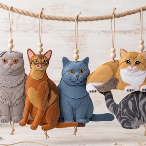 Può includere: Cinque ornamenti a forma di gatto in feltro, tra cui un Scottish Fold grigio, un abissino marrone, un British Shorthair blu, un gatto tigrato arancione e bianco e un gatto tigrato grigio. Ogni gatto è appeso a una corda di juta con una perlina.