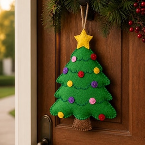 May include: A green felt Christmas tree ornament featuring a yellow star at the top and colorful circular button decorations. The tree has a brown trunk and is suspended by a jute twine loop, showcasing visible stitching along the edges.
