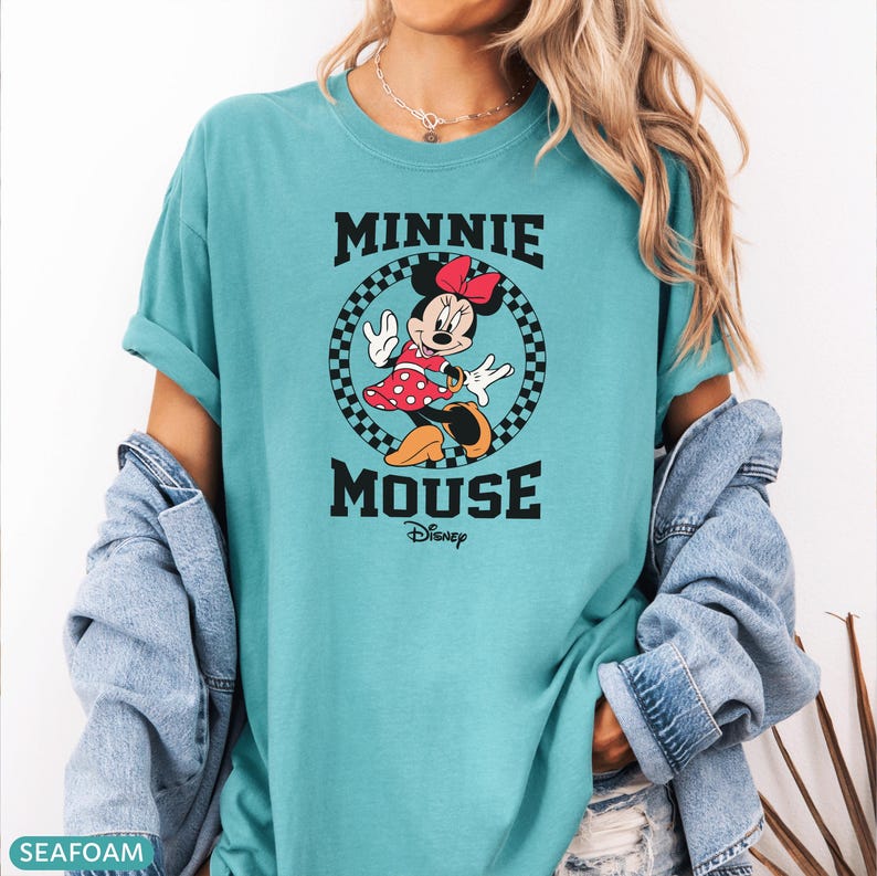 May include: Seafoam green t-shirt featuring a graphic of Minnie Mouse. The design includes the words "MINNIE MOUSE" in black block letters, with "Disney" below. Minnie is in a red polka dot dress and bow.