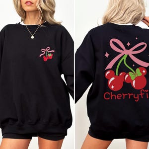 May include: A black long-sleeve sweatshirt featuring a small graphic of two red cherries shaped like mouse heads with a pink bow on the front left chest and a large matching graphic on the back with the text Cherryfic in red lettering.