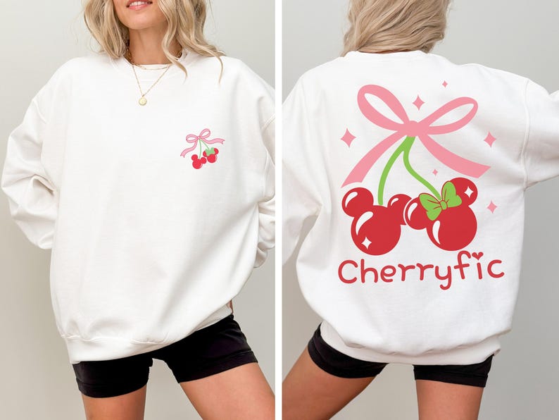 May include: A white long-sleeve sweatshirt featuring a small graphic of two red cherries shaped like mouse heads with a pink bow on the chest. The back displays a larger version of the same cherry graphic with the text Cherryfic in red font.