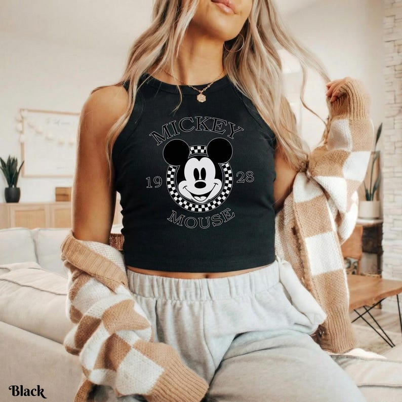 Op de afbeelding: Zwart tanktop met een Mickey Mouse-afbeelding. De afbeelding bevat de woorden "Mickey Mouse" en de cijfers "1928". De tanktop is mouwloos en heeft een ronde halslijn.