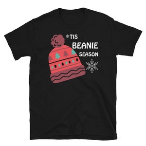 May include: Black t-shirt with a red and white beanie with a green and blue pattern and the text "*Tis Beanie Season" with a snowflake.
