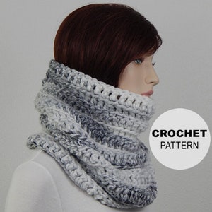 May include: A white and gray crocheted cowl neck warmer. The cowl is made with a chunky yarn and has a textured stitch pattern. CROCHET PATTERN is written in white text on a white circle.
