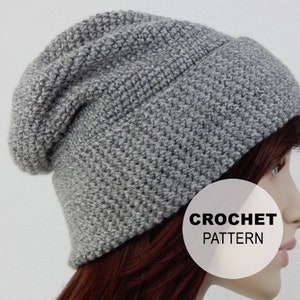 May include: Gray crochet beanie hat with a slouchy fit. The hat is made with a simple stitch pattern and has a ribbed brim. CROCHET PATTERN is written on a white circle in the image.