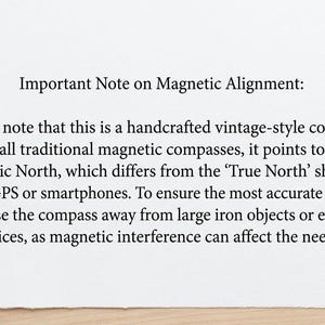 May include: A white card with black text that reads: Important Note on Magnetic Alignment: Please note that this is a handcrafted vintage-style compass. Like all traditional magnetic compasses, it points toward Magnetic North, which differs from the True North shown on digital GPS or smartphones. To ensure the most accurate reading, please use the compass away from large iron objects or electronic devices, as magnetic interference can affect the needle.