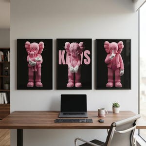Pu&ograve; includere: Tre stampe artistiche incorniciate raffiguranti personaggi rosa dei cartoni animati con occhi a forma di X e mani. Le figure sono ambientate su uno sfondo nero. Una figura tiene in mano una bambola, un'altra ha la scritta "KAWS" in rosa e la terza ha un dito sulle labbra.