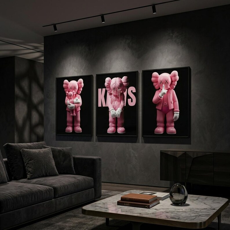 Pu&ograve; includere: Tre opere d'arte incorniciate con personaggi di cartoni animati rosa con occhi e mani a forma di X. Le figure sono su sfondo nero, con la parola "KAWS" in rosa su una di esse. L'arte &egrave; esposta in un moderno soggiorno.