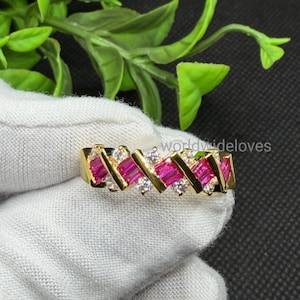 May include: A gold ring featuring a repeating pattern of rectangular, vibrant pink baguette-cut stones alternating with small, clear round-cut stones in a crisscross metal setting. The text "worldwideloves" is visible in the background.