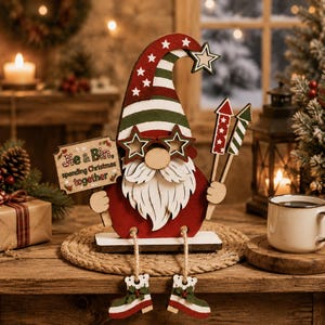 May include: A wooden gnome decoration featuring a red and green striped hat with white stars, star-shaped glasses, and a white beard. The gnome holds a sign that reads Jie & Bin, spending Christmas together and two firework-style sticks.