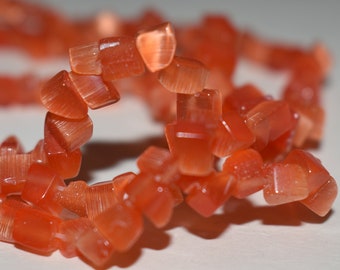 Bead, cat's eye glass, dark orange, small chip. Sold per 32-inch strand, chips range from small to large, necklace or supplies