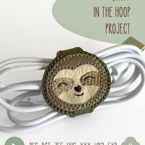 May include: A round, olive green cable organizer featuring an embroidered sloth face with cream and brown details, wrapped around a white USB cable. The text reads QUICK IN THE HOOP PROJECT and lists file formats .PES .DST .JEF .HUS .XXX .VP3 .EXP.