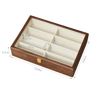 May include: A rectangular wooden storage box with a glass lid and a gold-tone latch. The interior features eight compartments lined in cream fabric. Dimensions are 13.78 inches long, 9.45 inches wide, 3.15 inches high, with 6.3 by 1.97 inch slots.