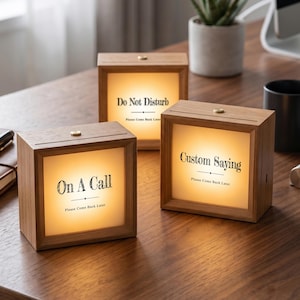 May include: Three square wooden light boxes with illuminated panels. The front panels display black text: On A Call, Do Not Disturb, and Custom Saying, each followed by the phrase Please Come Back Later. Each box features a small gold button on top.