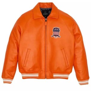 May include: Vibrant orange leather jacket with a zip closure, a collar, and a chest patch. The jacket features white and orange striped cuffs and hem. The patch displays a shield design with stars and stripes.