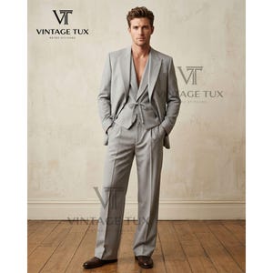 May include: A light gray, three-piece suit with a pinstripe design. The suit includes a blazer, vest, and wide-leg trousers. The vest has a tie at the waist. The image includes the text "VINTAGE TUX RETRO STITCHED".