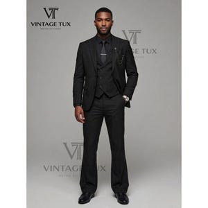 May include: A black three-piece suit with a matching tie and dress shoes. The suit includes a blazer, vest, and flared trousers. The image features the text "VINTAGE TUX" in the upper left corner.