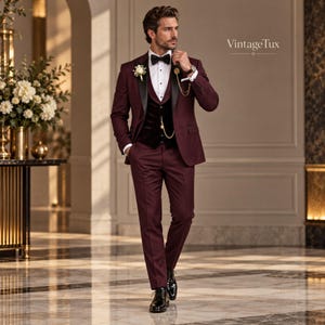 May include: A burgundy tuxedo suit featuring a black satin lapel, a matching black vest, a white dress shirt, and a black bow tie. The ensemble includes a gold pocket watch chain and a white boutonniere. The text VintageTux is visible.