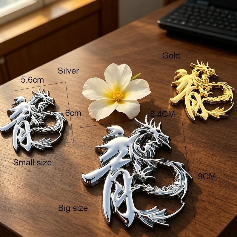 May include: Decorative dragon emblems in silver and gold. The silver emblems are labelled "Small size" (5.6cm x 6cm) and "Big size" (9cm x 8.4cm). A gold emblem is also shown. A white flower with a yellow center is also present.