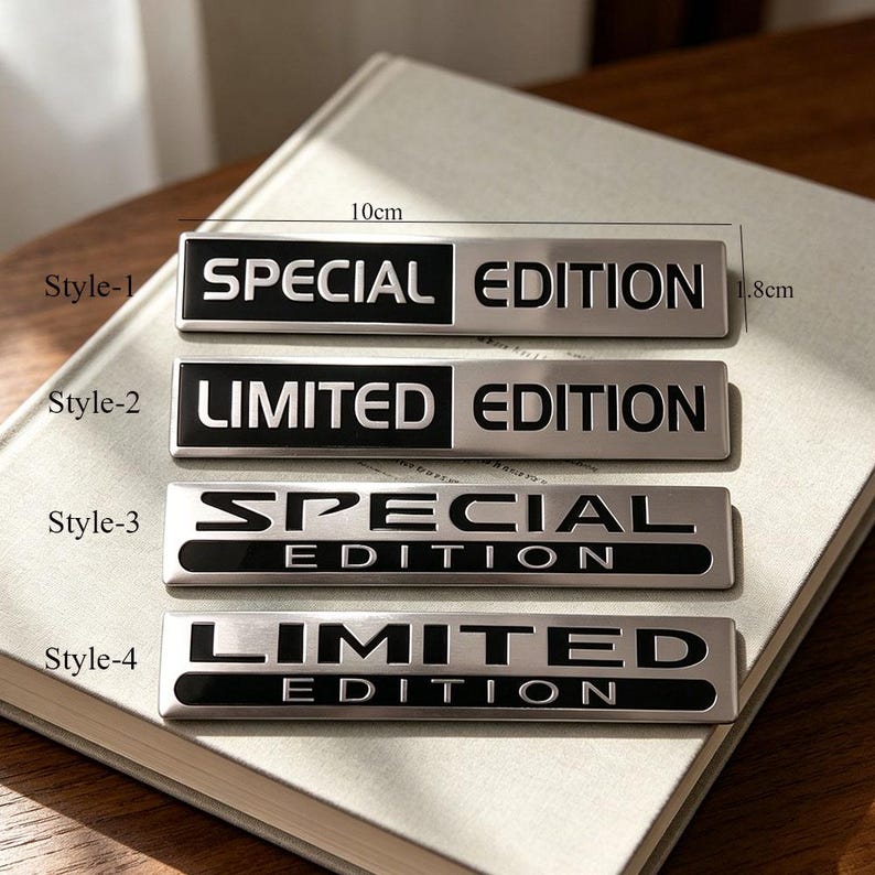 May include: Four rectangular metal badges with the words "SPECIAL EDITION" and "LIMITED EDITION" in black and silver. The badges are approximately 10cm long and 1.8cm wide. The badges are on a book.