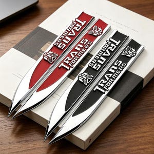 Peut inclure: Quatre emblèmes de voiture métalliques avec le texte "TRANSFORMERS" en lettres blanches. Deux emblèmes sont rouges et argentés, et deux sont noirs et argentés. Chaque emblème présente un logo de robot.