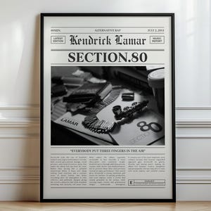 May include: Black and white framed poster featuring the text "Kendrick Lamar SECTION.80" in a newspaper-style layout. The image includes a close-up of items on a table, with the text "EVERYBODY PUT THREE FINGERS IN THE AIR" at the bottom.