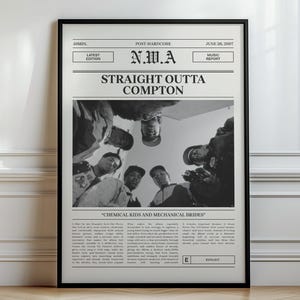 Può includere: Un poster incorniciato in bianco e nero con il testo N.W.A STRAIGHT OUTTA COMPTON in alto. Il centro mostra una fotografia dal basso di cinque persone che guardano verso il basso. Sotto l'immagine c'è un blocco di testo descrittivo e un'etichetta.