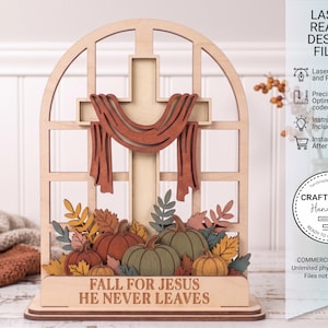 May include: A wooden laser-cut fall-themed decoration featuring a cross with a draped cloth, pumpkins, and autumn leaves. The base reads "FALL FOR JESUS HE NEVER LEAVES". The design is in shades of brown, orange, green, and yellow.