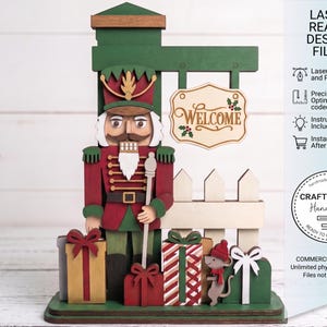 May include: A layered wooden nutcracker decoration featuring a green post with a hanging sign that reads WELCOME, a white picket fence, several wrapped gift boxes, and a small mouse. The text LASER READY DESIGN FILES is visible on the right.