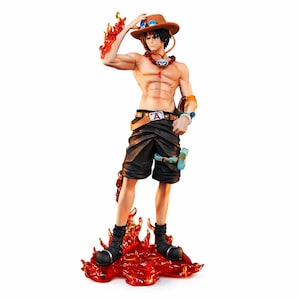 Peut inclure: Figurine détaillée d'un personnage musclé avec un chapeau marron et un short noir. La figurine a des flammes autour des bras et des pieds, et un collier. La figurine est posée sur une base rouge en forme de flamme.