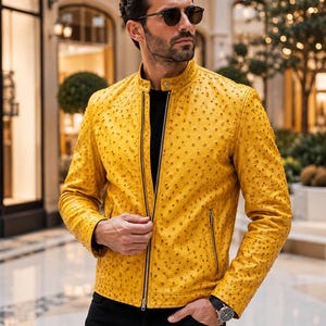 Peut inclure: Une veste jaune vif avec une surface texturée à pois, dotée d'un col officier, d'une fermeture éclair frontale en métal argenté et de deux poches latérales zippées verticales. La veste est portée sur un t-shirt noir et un pantalon noir.