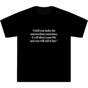May include: Black t-shirt featuring the quote "Until you make the unconscious conscious, it will direct your life and you will call it fate." in white text. The shirt has a round neck.