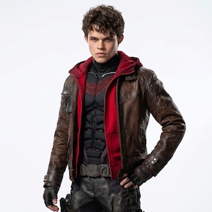 May include: A brown leather jacket with a red hooded lining worn over a black tactical chest piece with segmented plating. The outfit includes black fingerless gloves with red trim, a dark utility belt, and dark trousers against a white background.