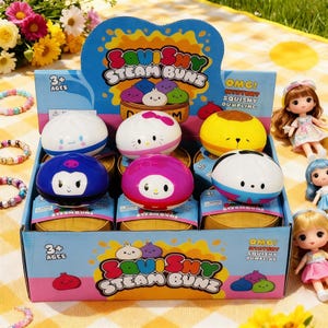 Puede incluir: Una caja de juguetes Steam Bunz blandos y coloridos, cada uno con un diseño de personaje único. La caja presenta el texto "Squishy Steam Bunz" y "OMG! Mystery Squishy Dumpling". Los juguetes están rodeados de pequeñas muñecas y pulseras.