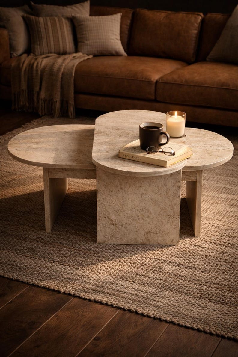 Peut inclure: Une table basse en deux parties avec une finition beige clair semblable &agrave; de la pierre. Un livre, des lunettes et une tasse de caf&eacute; sont pos&eacute;s sur la partie sup&eacute;rieure. Une bougie allum&eacute;e dans un support en verre est &eacute;galement sur la table.
