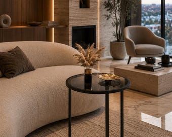 May include: A round side table with a black metal frame and a dark glass top. The table features a slender cylindrical base and a circular tabletop, holding a small vase with dried pampas grass and a shallow gold-toned decorative bowl.