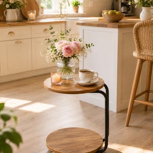 May include: A round two-tier side table with a dark wood finish and a black metal frame. The table features two circular shelves and is supported by a curved metal structure with small wheels at the base for mobility, providing a compact surface.