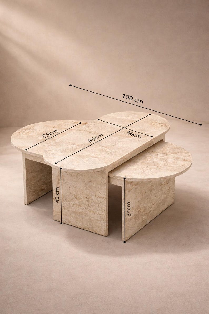 Peut inclure: Un ensemble de tables basses en deux parties, beige effet marbre. La plus grande table mesure 100 cm de long et 85 cm de large, avec une hauteur de 45 cm. La plus petite table mesure 36 cm de large et 37 cm de haut. Design moderne et minimaliste.