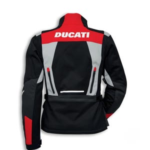 Pu&ograve; includere: Giacca da moto nera, rossa e grigia con la scritta "DUCATI" in bianco sulla parte superiore della schiena. La giacca ha un collo alto, tasche con cerniera e una striscia riflettente. Progettata per la guida in moto.