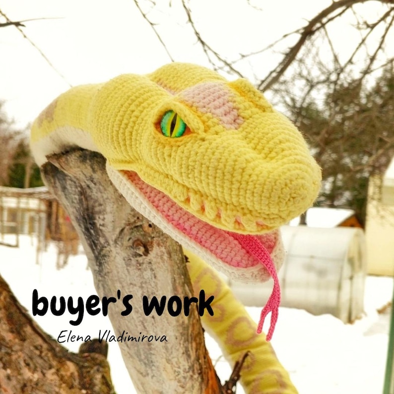 May include: A crocheted snake head in shades of yellow, pink, and white, with a pink tongue and green eyes. The snake is perched on a tree branch. The text "buyer's work" and the name "Elena Vladimirova" are visible.
