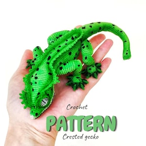 Könnte beinhalten: Ein gehäkelter grüner Kronengecko mit schwarzen Punkten wird in einer Hand gehalten. Der Gecko hat detaillierte Merkmale, darunter strukturierte Haut und einen eingerollten Schwanz. Das Wort "PATTERN" wird in grüner Schrift zusammen mit "Crested gecko" darunter angezeigt.