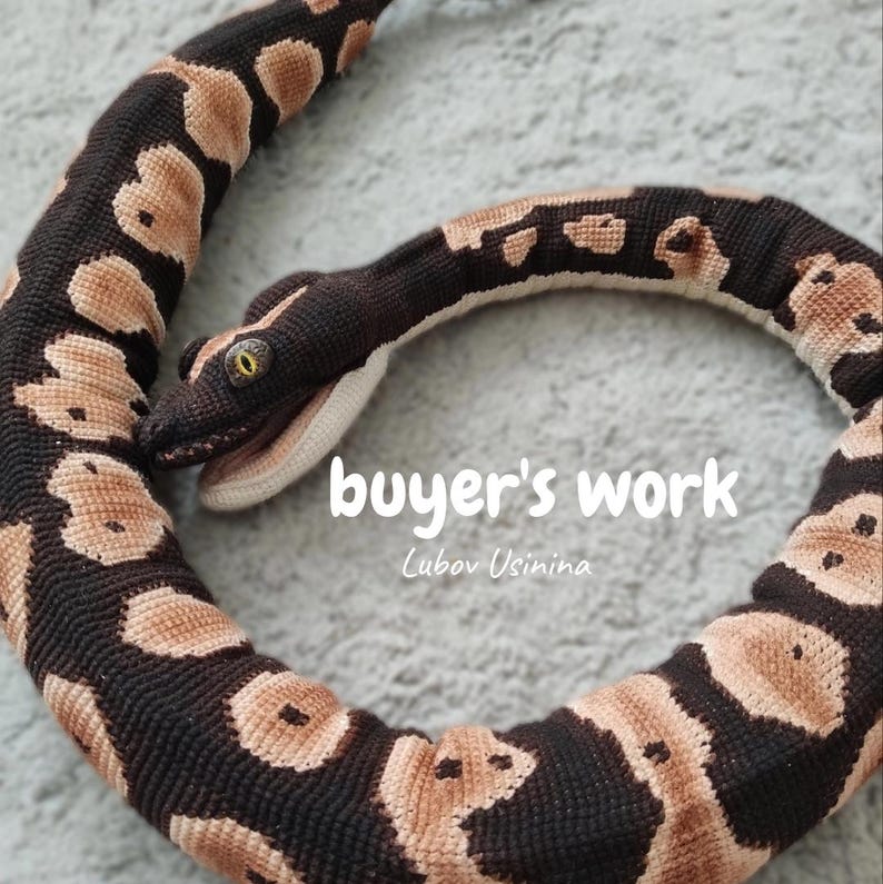 May include: A crocheted snake in shades of brown and beige, with yellow eyes. The snake is coiled and displays a detailed pattern. The image includes the text "buyer's work" and the artist's name.