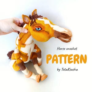 Puede incluir: Un caballo de ganchillo hecho a mano en tonos amarillos, marrones y blancos. El caballo tiene ojos azules y una melena y cola detalladas. La imagen incluye el texto "Horse crochet PATTERN by TotakSusha."