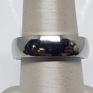 May include: A silver-toned wedding band with a rounded, polished surface.