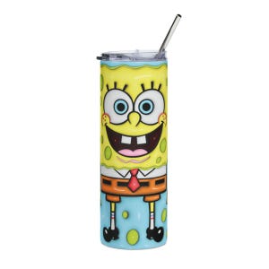 May include: A yellow tumbler featuring a cartoon character design. The tumbler has a stainless steel straw and a lid. The character has a large smile, blue eyes, and is wearing a red tie. The tumbler is cylindrical and has a blue base.