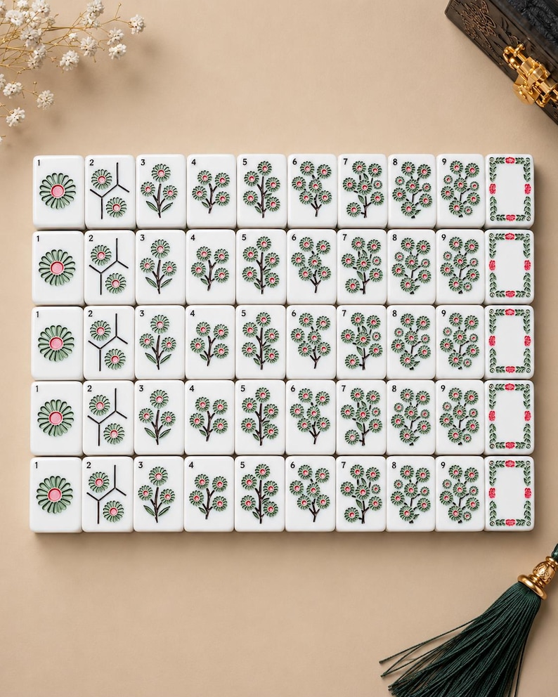 May include: A set of white rectangular mahjong tiles arranged in a grid, featuring engraved floral designs with green leaves and pink centers. Each tile displays a number from one to nine, with the final column showing a decorative floral border frame.