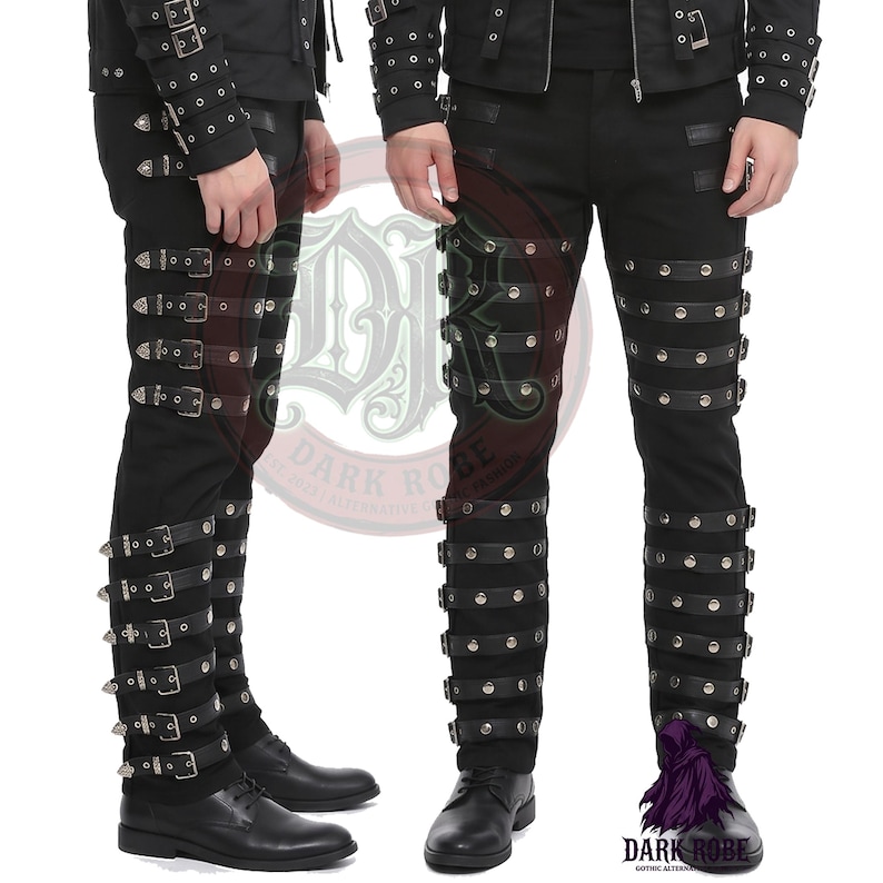 Op de afbeelding: Zwarte broek met meerdere rijen zilveren studs en zwarte leren riemen. De broek heeft meerdere gespen en wordt gedragen met zwarte schoenen. De afbeelding toont twee mensen die de broek dragen.