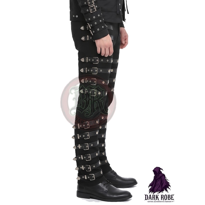 Op de afbeelding: Zwarte, kniehoge broek in gotische stijl met meerdere riemen en zilveren gespen. De broek heeft decoratieve metalen studs en wordt gecombineerd met zwarte geklede schoenen. De afbeelding bevat ook het Dark Robe-logo.